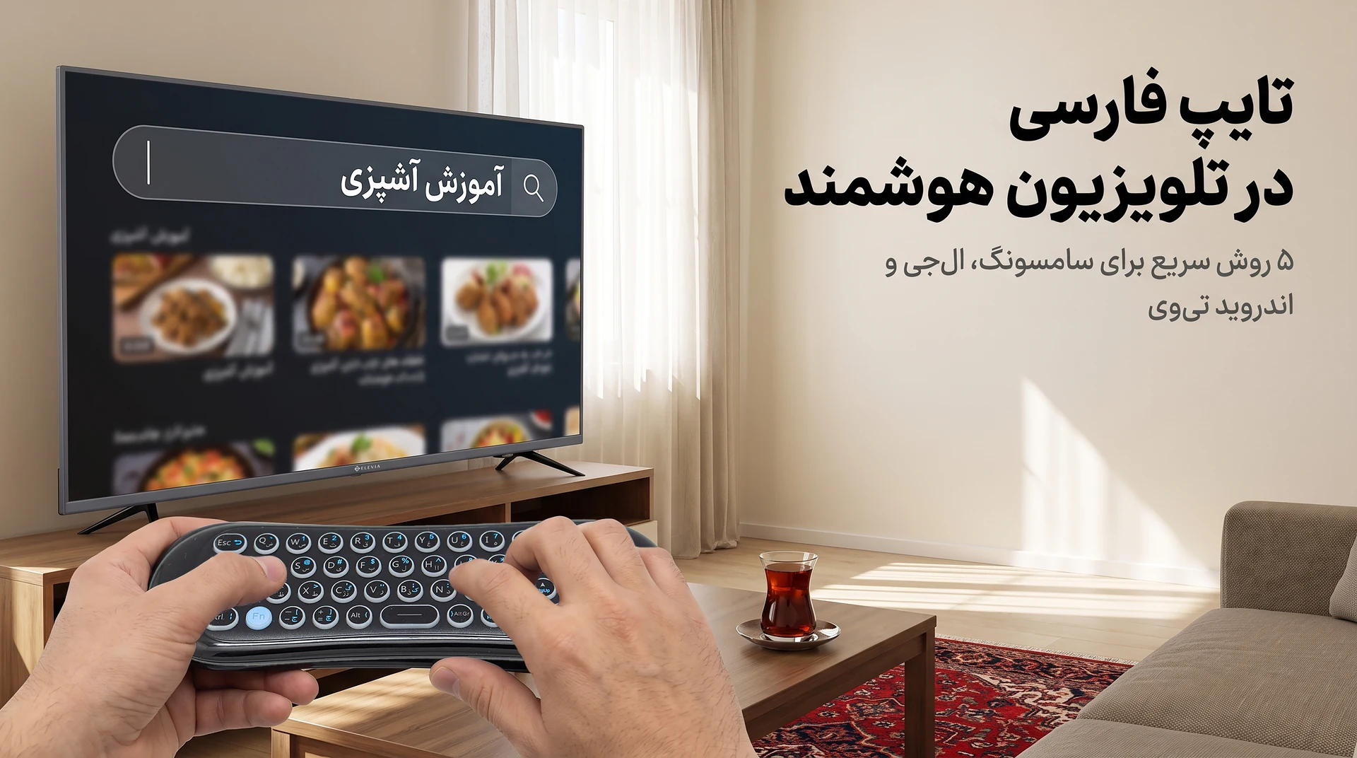 دو دست ایرموس کیبورددار الویا با کیبورد فارسی را نگه داشته‌اند و روی صفحهٔ تلویزیون هوشمند ۵۵ اینچ الویا در پذیرایی یک خانهٔ معمولی ایرانی عبارت «آموزش آشپزی» تایپ شده است